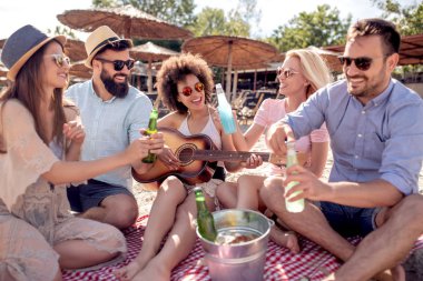 Genç arkadaşlar sahilde bir parti grup portresi.