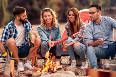 Kamp ızgara sosis ve birlikte zevk arkadaş grubu.