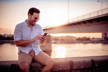 Genç adam cep telefonuna bakıyor..