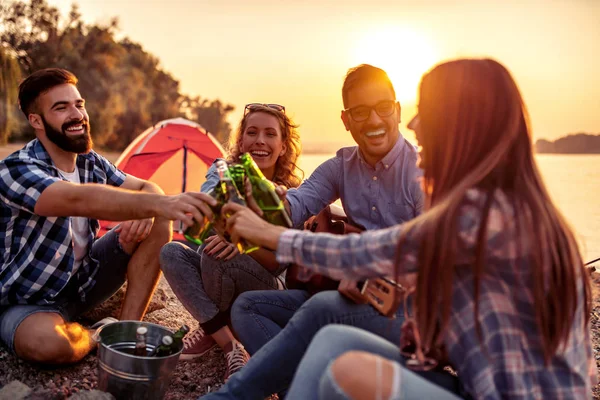 Group of excited friends having fun on the beach,playing guitar.