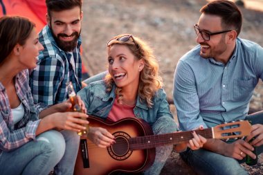 Heyecanlı genç arkadaşlar dan oluşan grup plajda birlikte eğlenir, bira içer ve kamp yaparken gitar çalar..