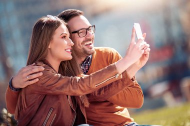Mutlu genç çift dışarıda eğleniyor, selfie çekiyor.