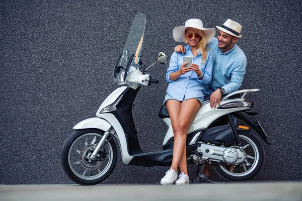 Scooter ride.Handsome guy and young beautiful woman posing on their scooter.