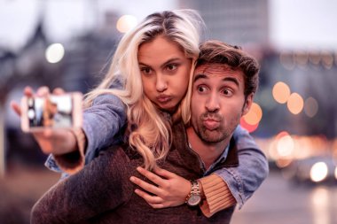 Mutlu genç çift şehir caddesinde selfie çekiyor.