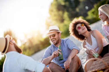 Sahilde birlikte eğlenen, soğuk birbira veya elma şarabı içen arkadaşlar.