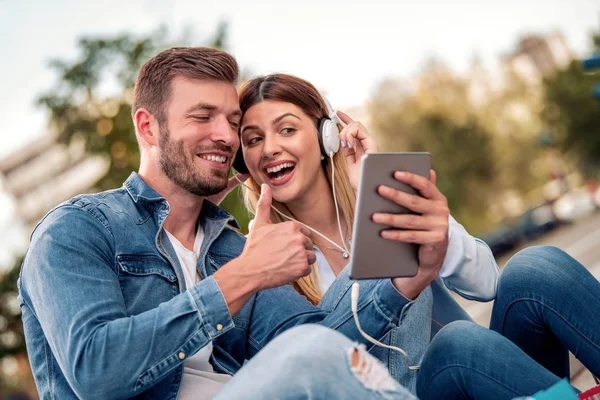 Young loving couple listening to music with tablet and headphones.