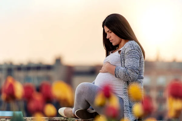 Kobieta Ciąży Siedzi Zewnątrz Dotykając Brzuch — Zdjęcie stockowe