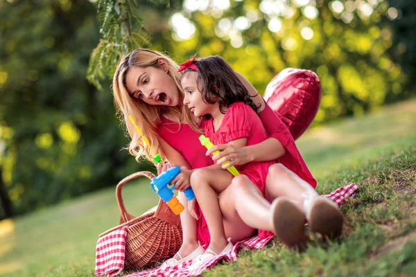 美しいお母さんと娘が公園でシャボン玉を吹いて — ストック写真