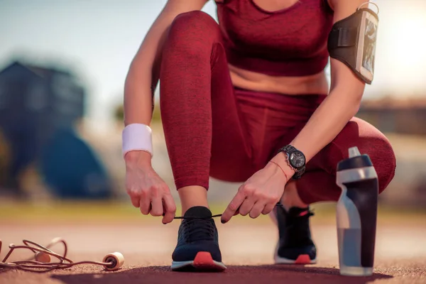 Close up of woman tying sport shoe on court in the morning.