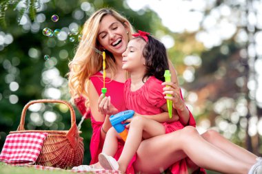 Küçük kız parkta annesi ile sabun köpüğü yapma.
