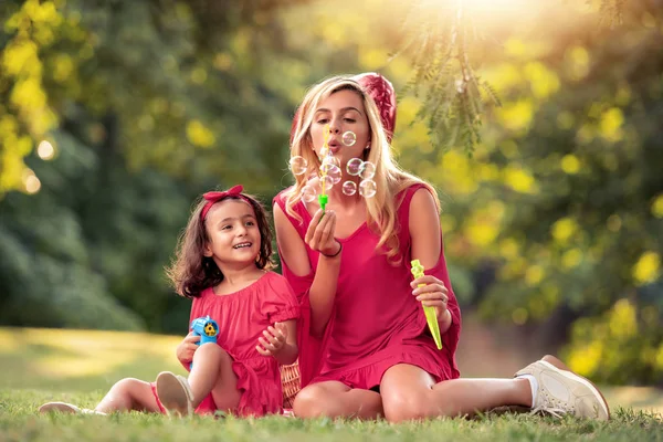 公園で石鹸の泡を吹く母と娘 — ストック写真