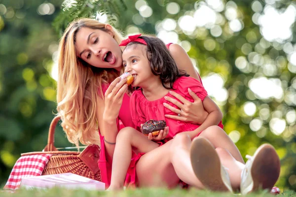 母と娘は公園でドーナツを食べて 楽しんでいます — ストック写真