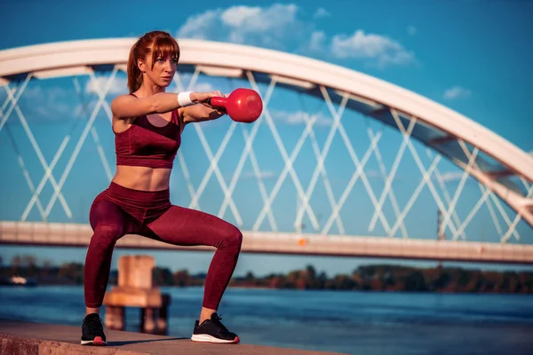 Fitness Vrouw Doet Squats Met Kettlebell Buiten Met Grote Brug — Stockfoto