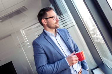 İşadamı kahve içiyor, pencereden bakıyor ve mola veriyor.