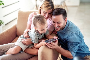 Mutlu aile birlikte evde zevk, tablet kullanma ve birlikte iyi vakit geçiriyor.