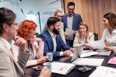 Ofiste otururken çalışan ve iletişim kuran bir grup iş adamı.