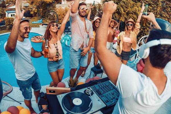 Enjoying pool party with friends.Group of friends having party by swimming pool.