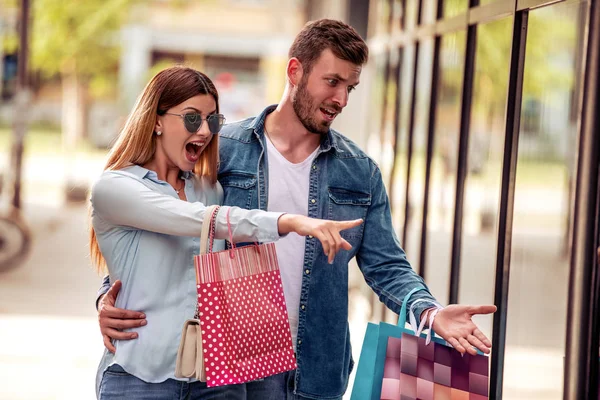 快乐的年轻夫妇与购物袋走在附近的商店窗口在城市 — 图库照片