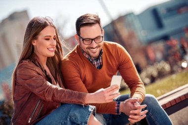 Mutlu genç çift dışarıda eğleniyor, selfie çekiyor.