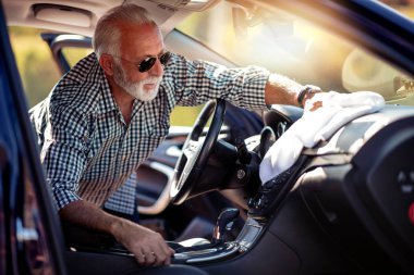 Kıdemli adam yeni arabasının içini temizliyor..