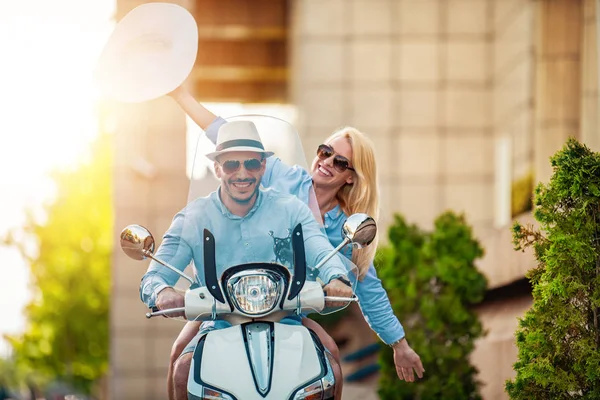 Cheerful couple in love on scooter driving together.