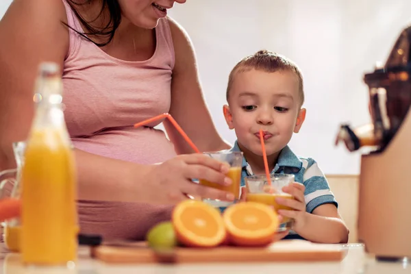 Gravid mor och son gör juice — Stockfoto