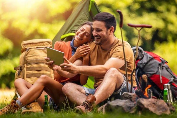 Couple sitting in front of tent. Camping in forest.