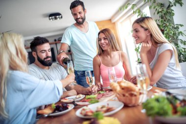 Bir grup neşeli genç, evde lezzetli yiyeceklerle eğleniyor..