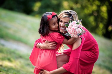 Anne kızını kucağında tutuyor ve yaz günü parkta oynuyor..