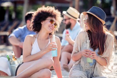 Kumsalda oturup bira içen iki dost..