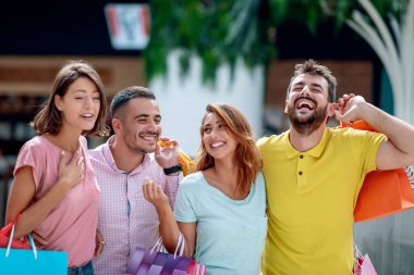 Alışveriş yaptıktan sonra ellerinde alışveriş torbalarıyla şehirde bir grup genç arkadaş..