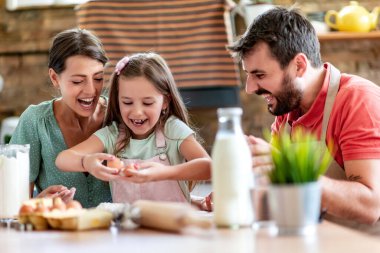 Mutfakta mutlu bir aile var. Anne, baba ve kız hamuru hazırlıyor..