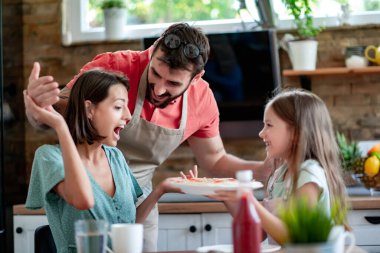 Genç bir aile evde birlikte pizza hazırlıyor..