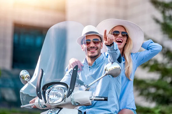 Happy couple on scooter driving in the city.