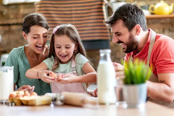 Mutfakta mutlu bir aile var. Anne, baba ve kız hamuru hazırlıyor..