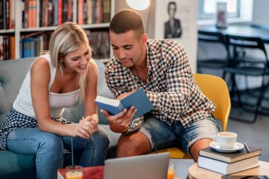 Couple of  students are studying together in the library. Education, dating, university and lifestyle concept.