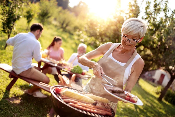 食べ物 家族の時間の概念 夏の庭のパーティーでバーベキューグリルで肉を焼く上級女性 — ストック写真