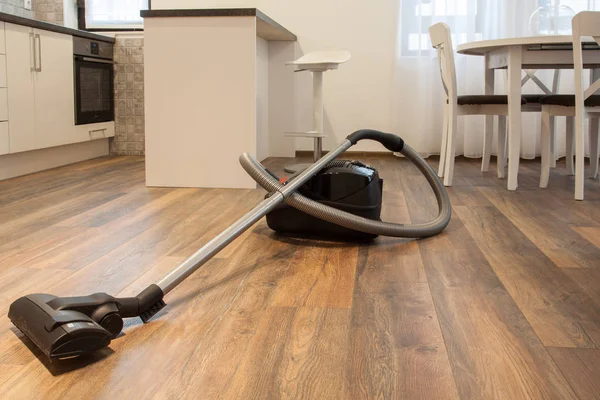 Vacuum cleaner on the wooden floor. Cleaning home