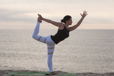 Pratik yoga sahilde kadın. Kral dansçı poz, Natarajasana. Açık havada spor. Sağlıklı yaşam.