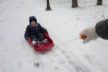 Onun kızak kış karda mutlu küçük çocuğa
