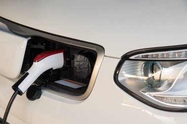 Elektrikli araba aküsünü şarj et. Şarj istasyonunda elektrik kablosu takılı elektrikli araba.