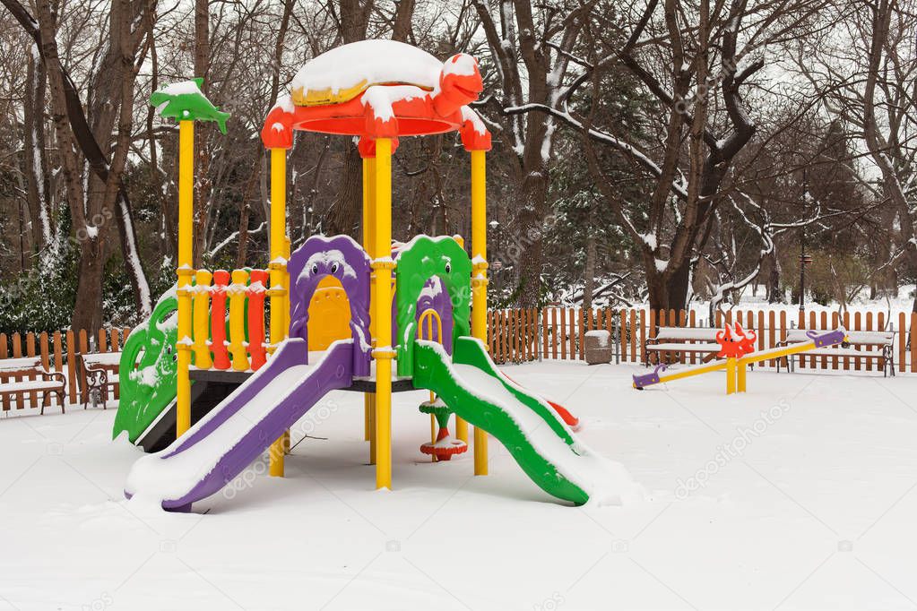 Empty snow children playground in the park in winter time
