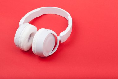 Kırmızı arka planda kablosuz beyaz kulaklık. Müzik konsepti. Kırmızı arkaplanda kulaklıklar. 