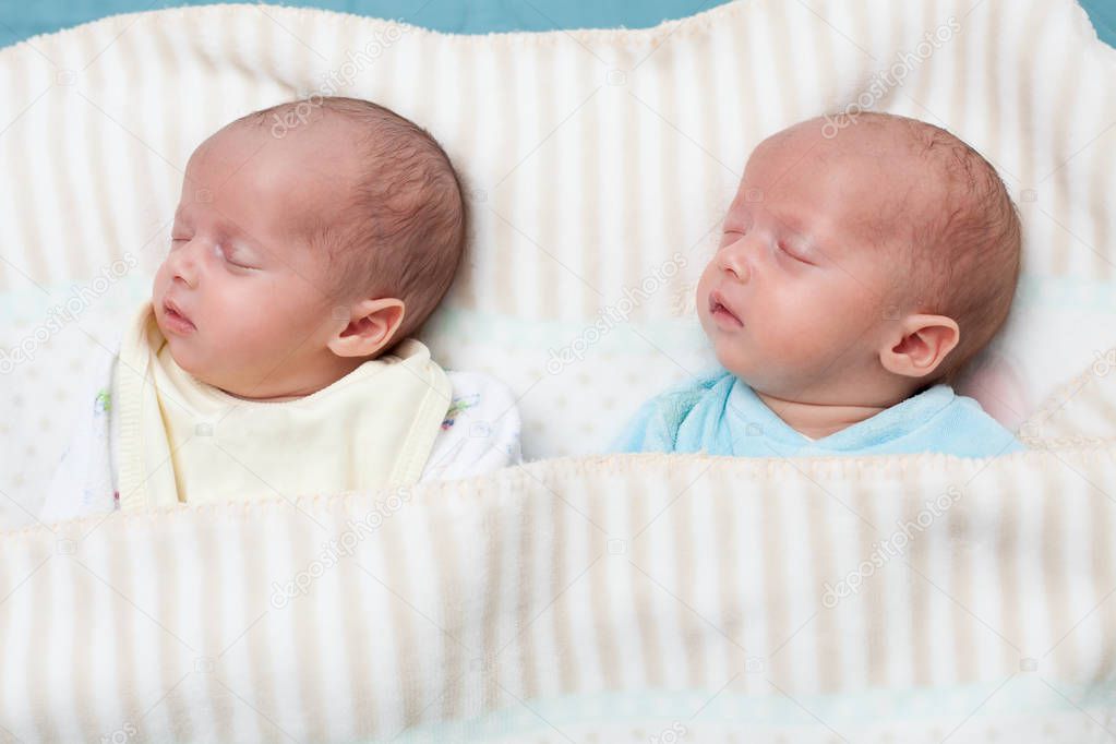 Two adorable twin babies sleeping in the same pose. Closeup portrait, caucasian child