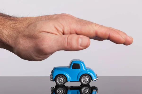 Liten retro, blå bil som täcker med manlig hand. Skydd, bil försäkring. — Stockfoto
