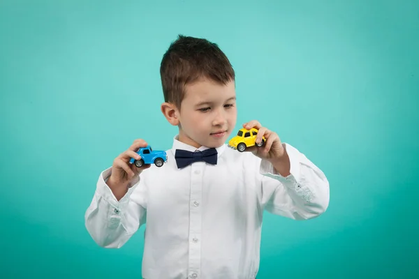 Niedlicher kleiner Junge mit weißem Hemd und Fliege, der mit Autos spielt — Stockfoto