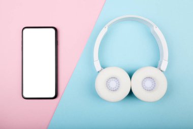 Akıllı telefon, mavi ve pembe arka planda kablosuz beyaz kulaklıklı cep telefonu. Müzik dinlemeye hazır.