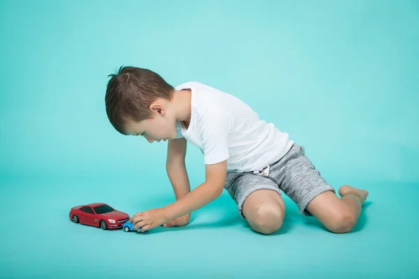 Little boy plays with toy cars on green background — Stock Photo, Image