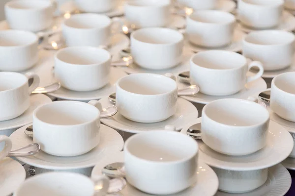 Rader av rent vitt kaffe eller te koppar, skålen och sked i en cafeteria eller restaurang redo att servera en varm dryck — Stockfoto
