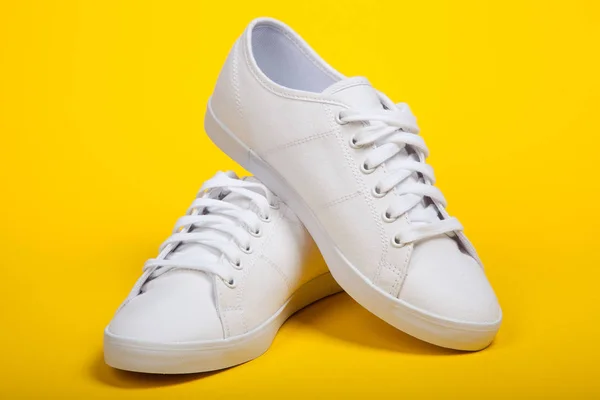 Paire de nouvelles baskets blanches sur fond jaune — Photo